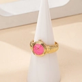 Detailed view of creative watch-shaped ring with pink dial and golden metal texture - Pink
