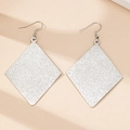 Macro shot of silver rhombic drop earrings with frosted glitter texture and elegant finish - White Gold