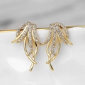 Detailed macro shot of gold tassel earrings with zircon pavé on a ceramic edge - Gold Winged Dangle