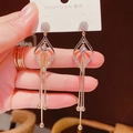 Gros plan de boucles d'oreilles dorées géométriques avec cristaux et franges longues - Gland Losange Or