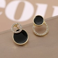 Vue macro de boucles d'oreilles géométriques dorées avec émail noir et cristaux blancs - Clou Disque Noir Doré