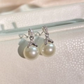 Detail view of pearl earrings with curved zircon-set hooks on a luxury display stand - Bowknot Freshwater Pearl Style (EP6048-White Pearl Platinum Plated)