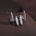 Dettaglio macro di orecchini curvi in argento con zirconi lucidi su base in pelle scura - Stile Geometrico Ondulato Incrociato (EP6018-Argento)