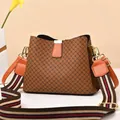 Close-up of brown quilted bucket bag with colorful striped wide strap and gold hardware - Grid/Earth Yellow