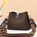 Detailed macro view of brown diamond pattern bucket bag with striped canvas wide shoulder strap - Grid/Coffee