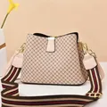 Detail of beige bucket bag with diamond lattice pattern and striped canvas shoulder strap - Grid/Apricot