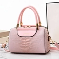 Detail of pink lizard texture bucket bag featuring gold zippers and hardware accents - Pink