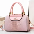 Detailansicht der hellrosa Tasche mit Eidechsenprägung, Känguru-Logo und Goldbeschlägen - Rosa