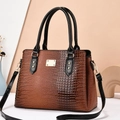 Detail of lizard-embossed texture on a classic trapezoid brown handbag with black handles - Khaki/Earth Yellow