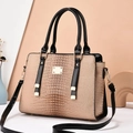 Detail of beige lizard texture leather bag with black handles and golden metal hardware - Khaki
