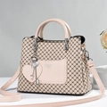 Detail of nude pink tote with black X patterns and heart charm pendant on side - Quilted Cream
