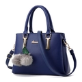 Détail d'un sac à main bleu marine en cuir grainé avec finitions dorées et pompon - Bleu foncé