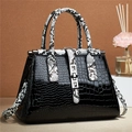 Detail of black crocodile texture handbag featuring snake pattern straps and silver buckle - Black