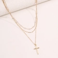 Close-up of golden multi-layer necklace with white pearls and a cross pendant detail - Gold