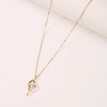 Elegant gold necklace with curved pendant and sparkling round zircon on textured background - Gold