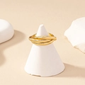 Minimalist golden multilayer trinity ring interlaced on white conical jewelry display - Gold