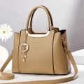 Detalle del bolso tote de cuero con grano de lichi, asa dorada y colgante perla - Caqui