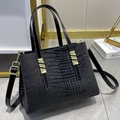 Chic black crocodile embossed tote bag with gold hardware and adjustable strap on marble floor - Black