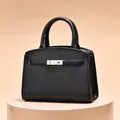 Sac à main structuré en cuir noir avec fermoir doré sur socle beige élégant - Noir