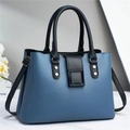 Detail of blue and black contrast leather handbag showing litchi texture and metal rivets - Blue