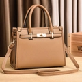 Brown lychee leather tote bag with gold buckle and adjustable strap on a wood table - Khaki/Earth Yellow
