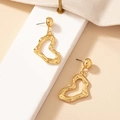 Orecchini a cuore dorati moderni con texture lavica su superficie in marmo chic - Stile Cuore d'Oro