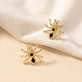 Modische Gold-Ameisenohrringe mit schwarzem Emaille-Detail auf weißem Stoffhintergrund - Goldene Spinne Stil (E048-蚂蚁)