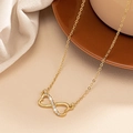 Gouden infinity-ketting met dubbel hart en sprankelende kristallen op zacht breigoed - Goud