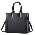 Close-up of floral embossed texture and golden metal hardware on black leather tote - Black