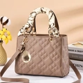 Elegant taupe quilted handbag with silk scarf handle and golden hardware on books - Khaki