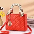 Red quilted square handbag with silk scarf handle and metal charm in a stylish setting - Red