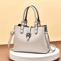 Detailed view of cream PU leather handbag with metal flower clasp on display stand - Beige Grey