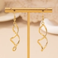 Elegant gold spiral drop earrings displayed on a T-shaped stand with soft beige background - Gold