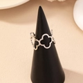 Fashionable hollow clover open ring in silver metal finish displayed on a dark stand - Silver
