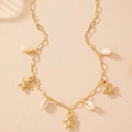Flache Ansicht von goldenen Seesternen und weißen Kauri-Muscheln auf sandigem Hintergrund - Seestern und Muschel Anhänger Stil / Gold