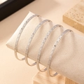 Set de cuatro brazaletes plateados con patrón de rombos en un rollo de joyería crema - Set de 4 piezas / Color Oro Blanco (Juego de 4)