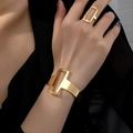 Set minimalista con bracciale e anello geometrici cavi dorati indossati da una modella - Oro