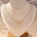 Collana minimalista con fiocco dorato su catena a O esposta su un busto per gioielli - Oro