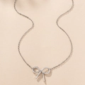 Vista piatta macro della collana con pendente a fiocco d'argento su sfondo beige - Argento
