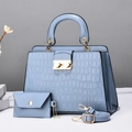Vista macro della borsa tote azzurra a stampa coccodrillo con anelli dorati e borsetta - Blu