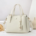 Detailed macro of minimalist off-white pebble leather bag with premium gold hardware accents - White