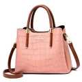 Detailed view of pink crocodile-embossed leather and golden logo on fashion handbag - Pink Crocodile Pattern