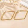 Makroaufnahme von goldenen geometrischen Rautenohrringen mit Hochglanzfinish auf Display - Gold