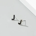 Detailed view of silver letter J stud earrings with black enamel inlay and soft shadows - Letter J