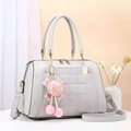 Close-up of light grey quilted tote bag with golden hardware and pink pompom charm - Light Gray