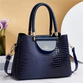Dunkelblaue Handtasche mit Krokodilprägung und goldener Schrift auf Marmorhintergrund - Blau