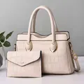 Detail of cream faux crocodile texture handbag set with elegant gold hardware - White