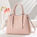 Pink textured crossbody bag with square embossing and top handles in a stylish setting - Pink