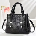 Detailed view of black woven texture leather handbag with silver metallic hardware - Black