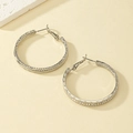 Macro shot of silver textured hoop earrings with a twisted metal finish and C-shape design - White Gold